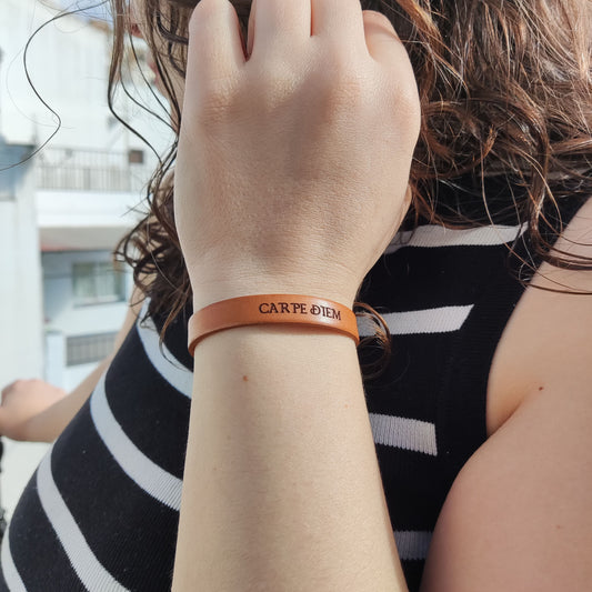 A brown leather bracelet with the phrase `Carpe Diem´ engraved on it.