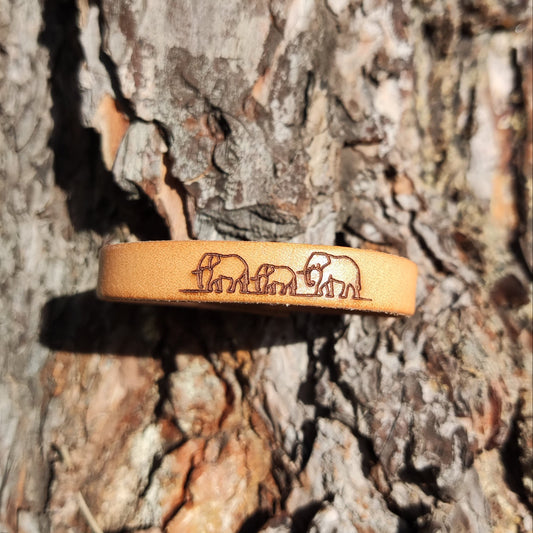 A brown leather bracelet with elephants engraved on it.