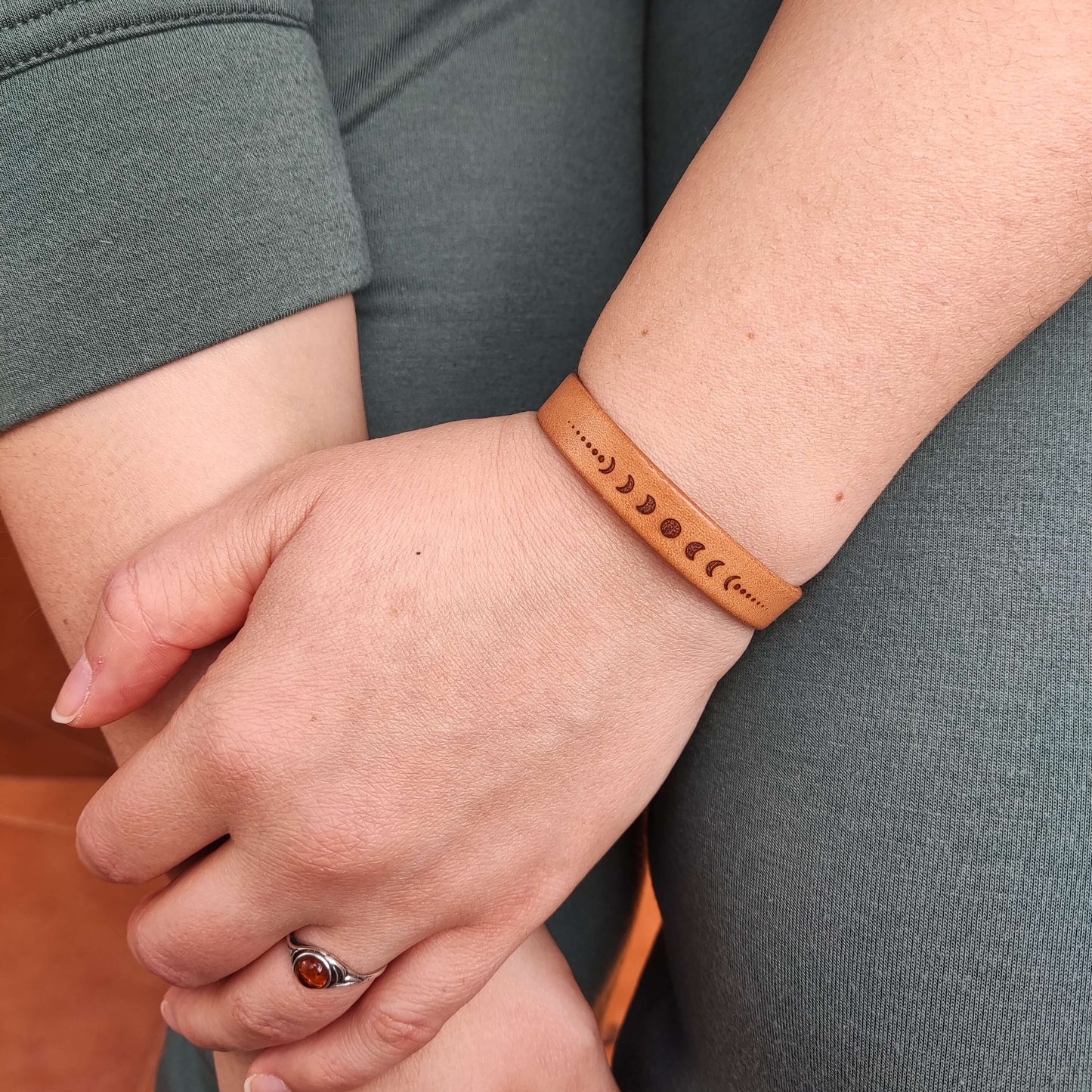 A brown leather bracelet with the lunar phases engraved on it.