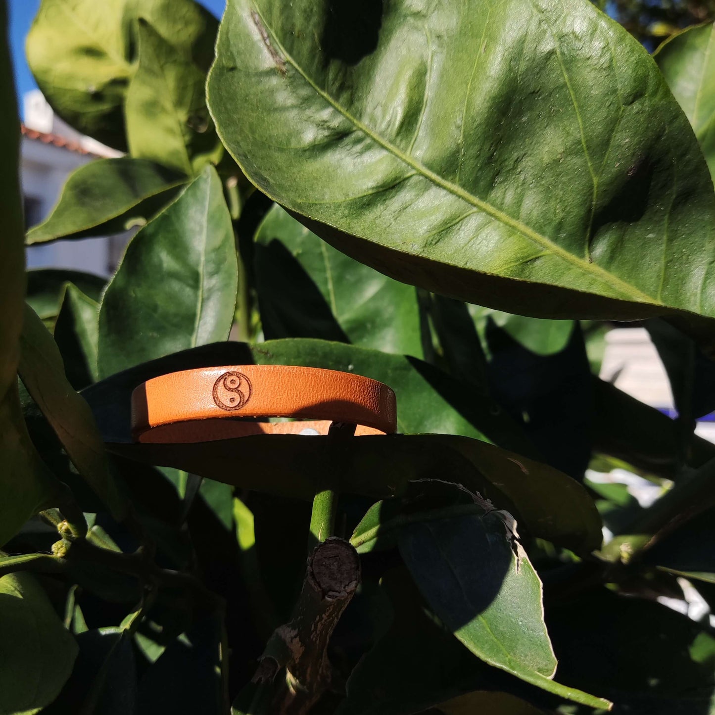 A brown leather bracelet with the Yin Yang symbol engraved on it.