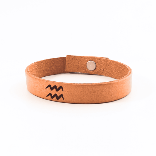 A brown leather bracelet with Aquarius´  symbol engraved on it.