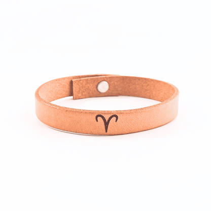 A brown leather bracelet with aries´ symbol engraved on it.
