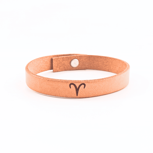 A brown leather bracelet with aries´ symbol engraved on it.