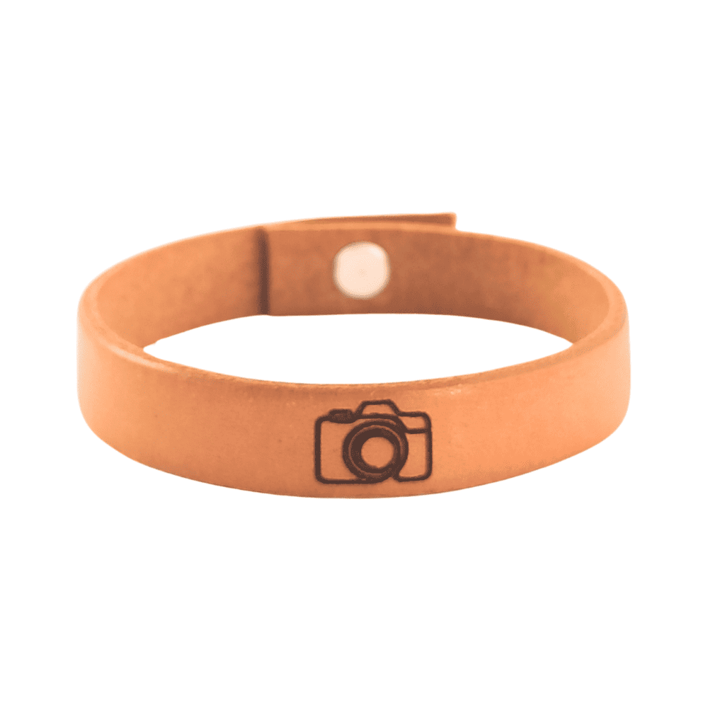 A brown leather bracelet with a camera engraved on it.