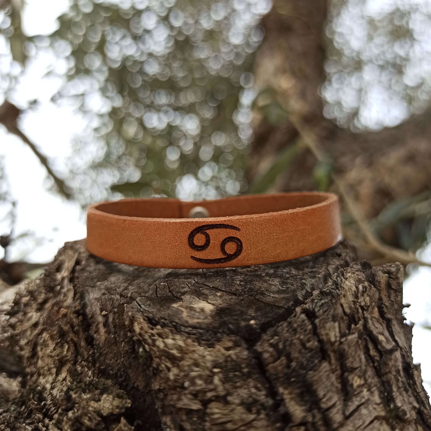Brown leather bracelet with cancer´s  symbol engraved on it.