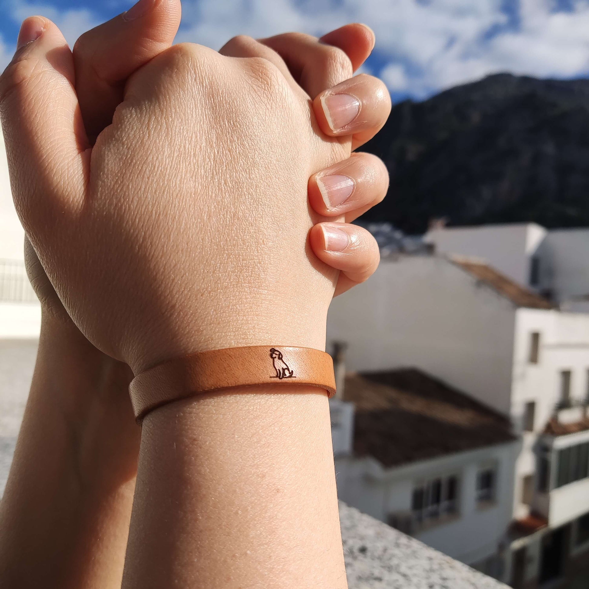 A brown leather bracelet with a dog engraved on it.