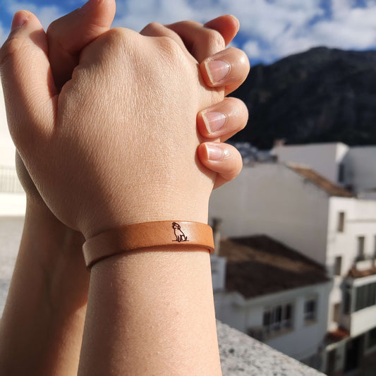A brown leather bracelet with a dog engraved on it.
