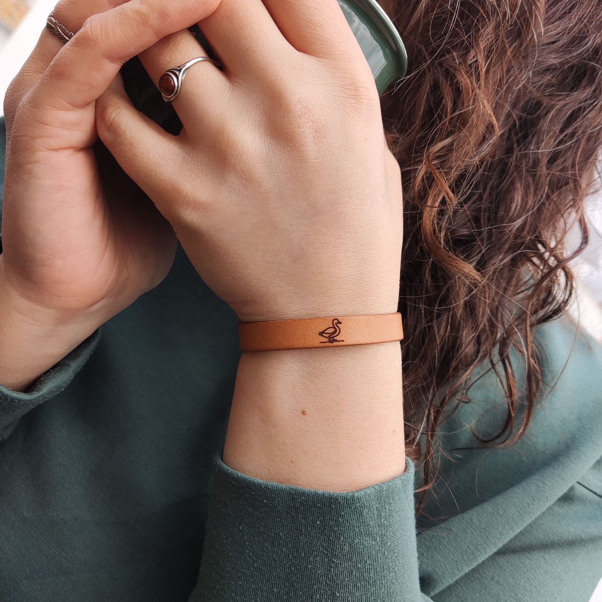 A brown leather bracelet with a duck engraved on it.