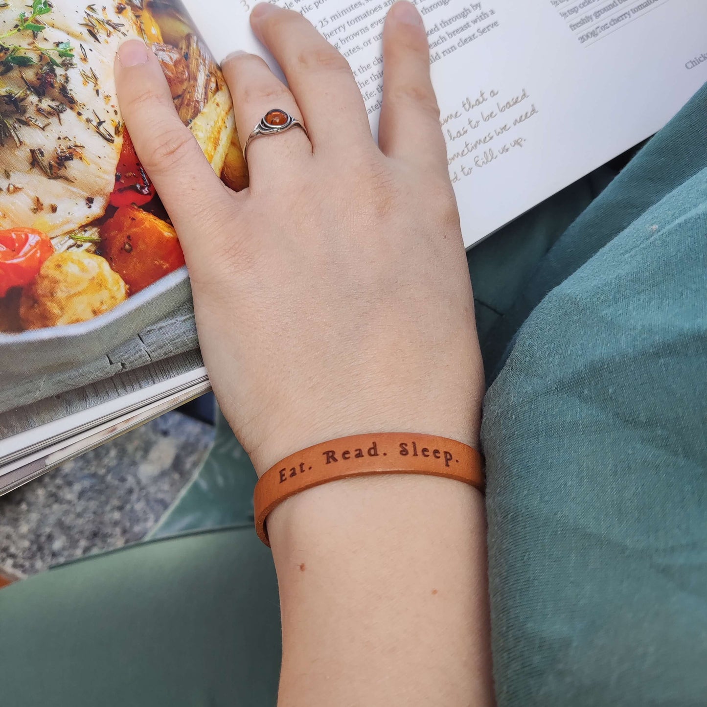 A brown leather bracelet with the phrase `Eat.Read.Sleep.´ engraved on it.