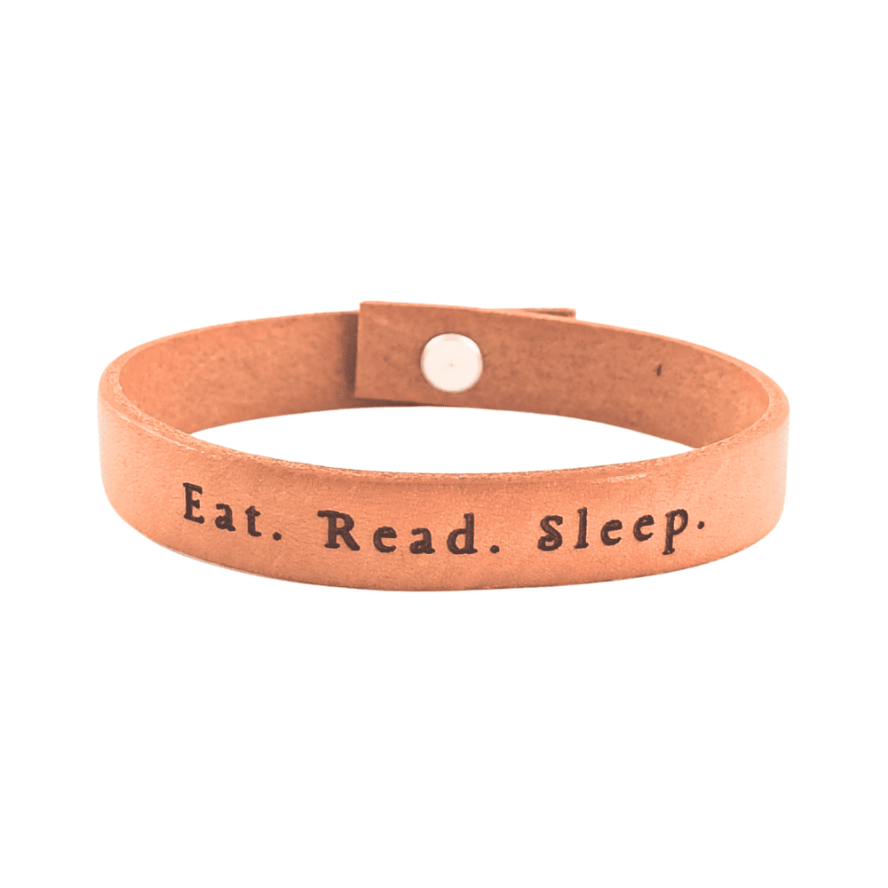 A brown leather bracelet with the phrase `Eat.Read.Sleep.´ engraved on it.