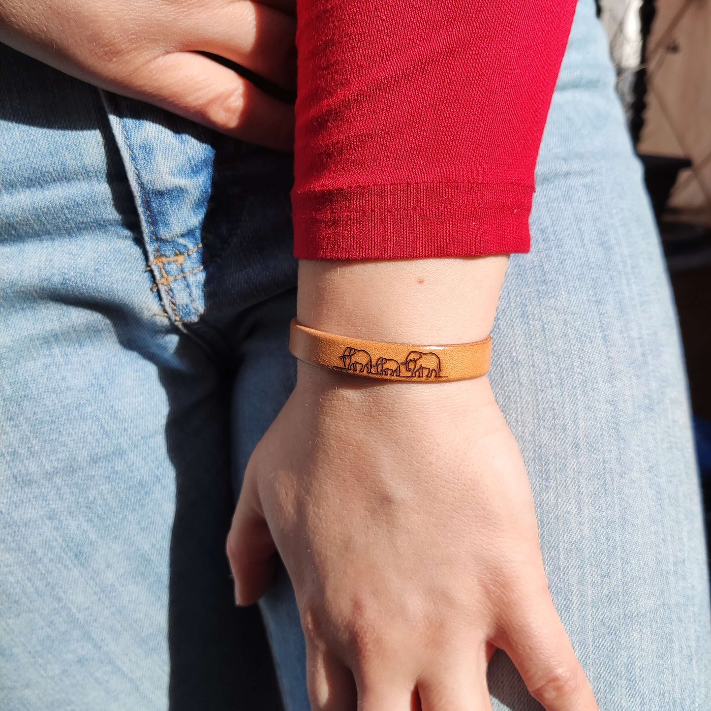 A brown leather bracelet with elephants engraved on it.