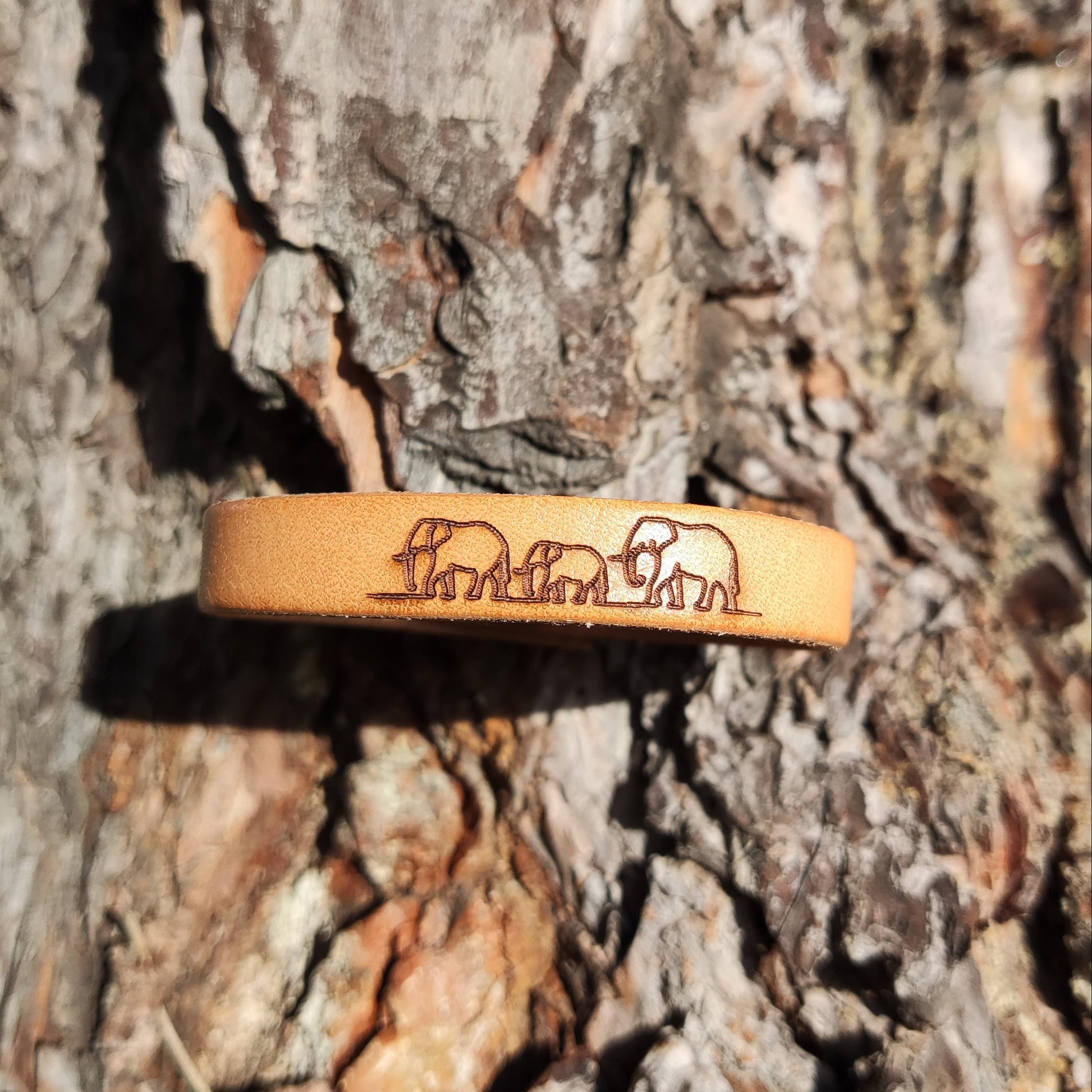 A brown leather bracelet with elephants engraved on it.