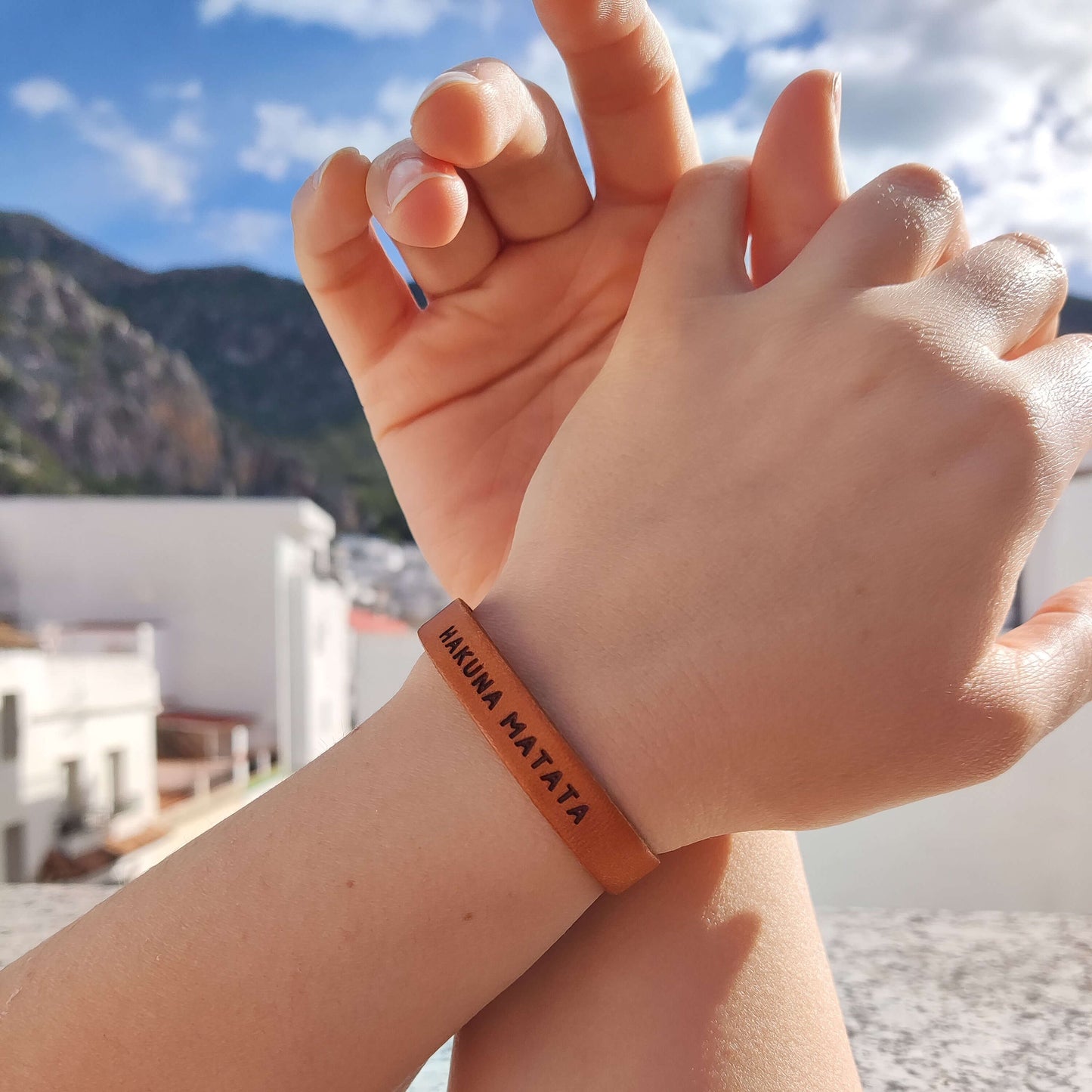 A brown leather bracelet with 'Hakuna Matata' engraved on it.