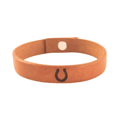 A brown leather bracelet with a horseshoe engraved on it.