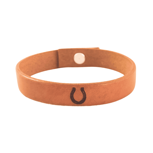 A brown leather bracelet with a horseshoe engraved on it.