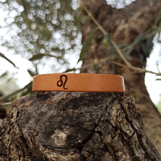 A brown leather bracelet with Leo´s symbol engraved on it.