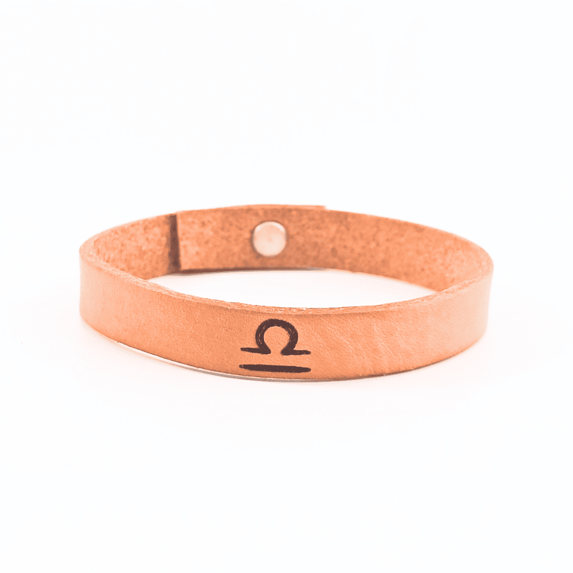A brown leather bracelet with libra´s symbol engraved on it.