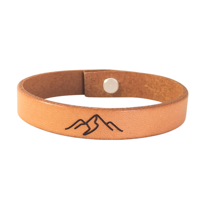 A brown leather bracelet with mountains engraved on it.