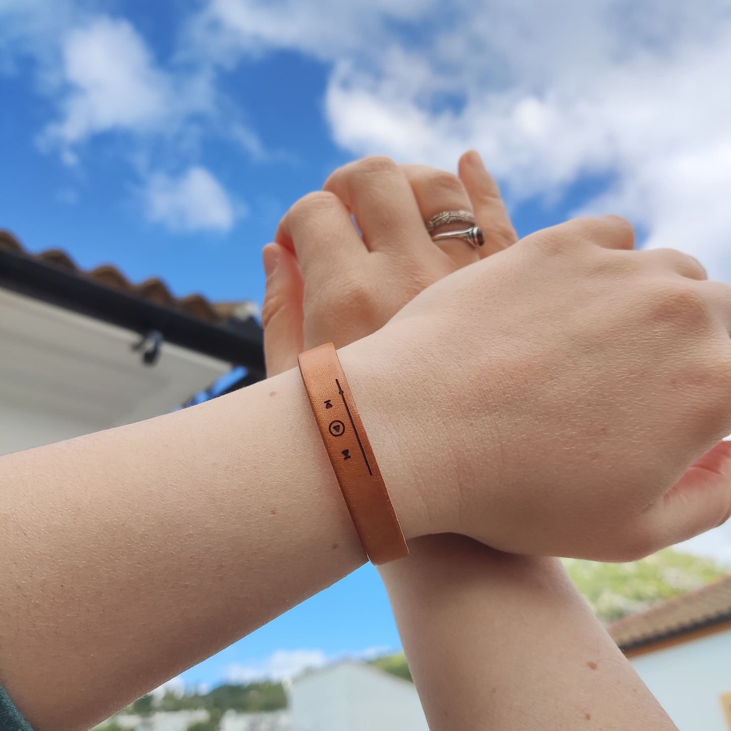 A brown leather bracelet with musical track slider engraved on it.