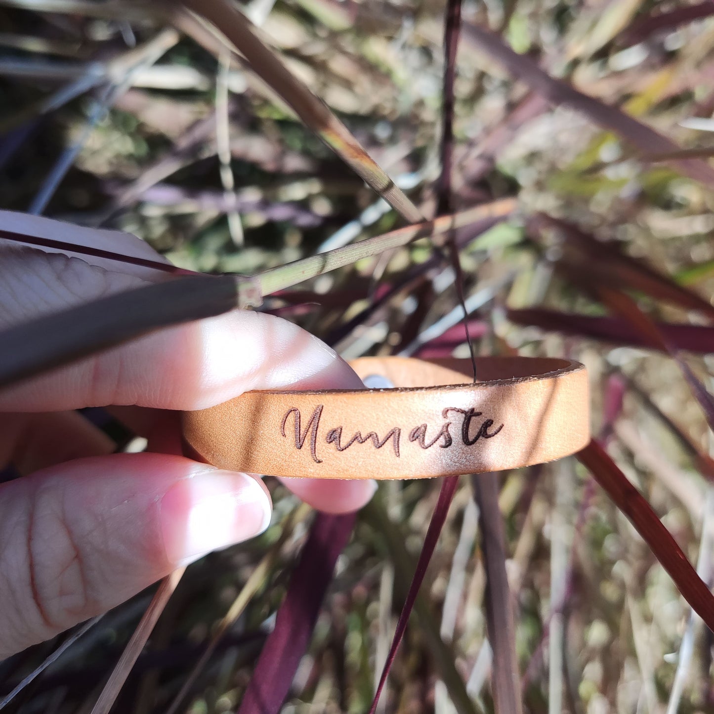 A brown leather bracelet with the phrase `Namaste´ engraved on it.