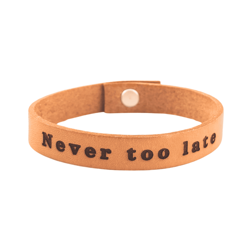 A brown leather bracelet with the phrase `Never too late´ engraved on it.