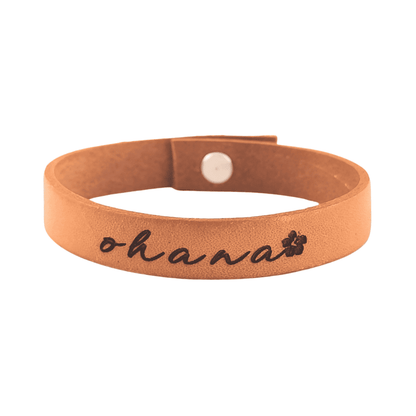 A brown leather bracelet with the phrase `Ohana´ engraved on it.