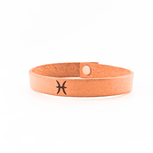 A brown leather bracelet with pisces´ symbol engraved on it.