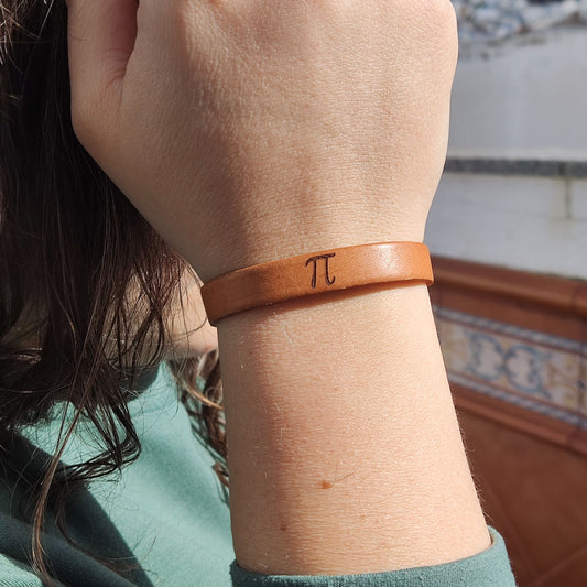A brown leather bracelet with the pi symbol engraved on it.