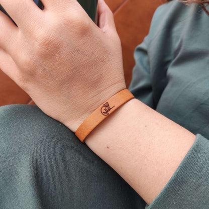 A brown leather bracelet with a  red panda engraved on it.