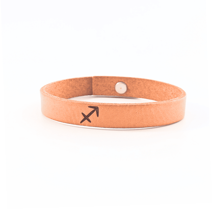 A brown leather bracelet with sagitarrius´ symbol engraved on it.