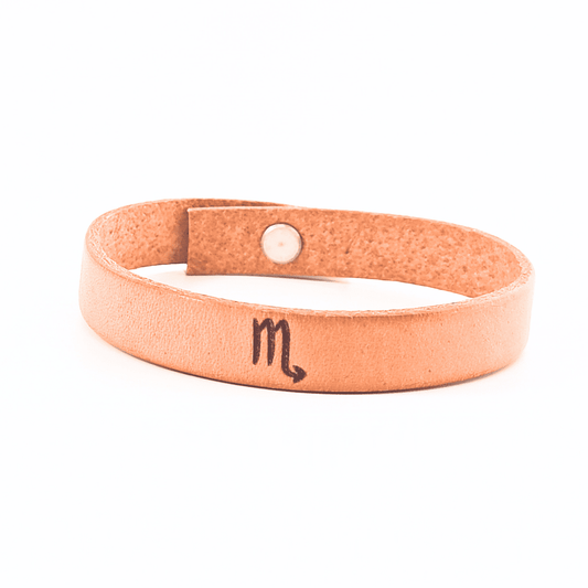 A brown leather bracelet with scorpio´s symbol engraved on it.
