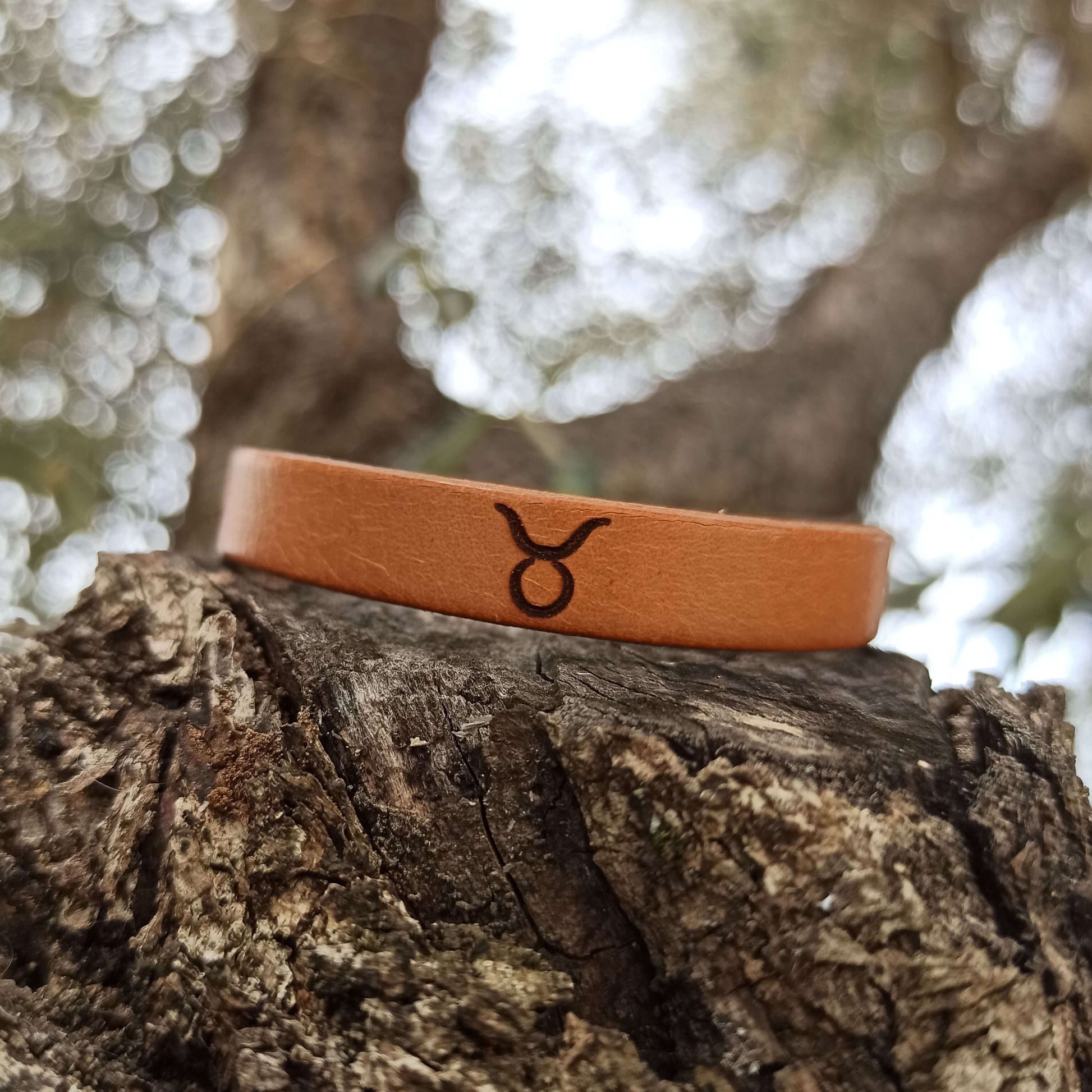 A brown leather bracelet with taurus´ symbol engraved on it.