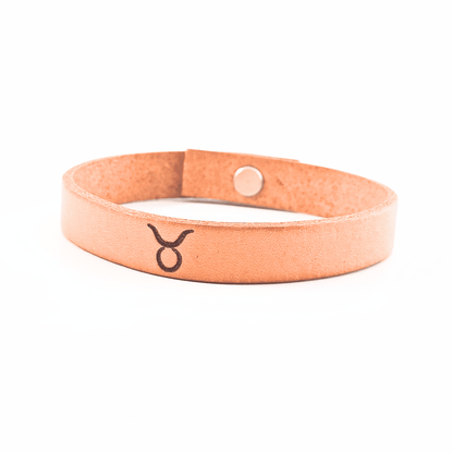 A brown leather bracelet with taurus´ symbol engraved on it.