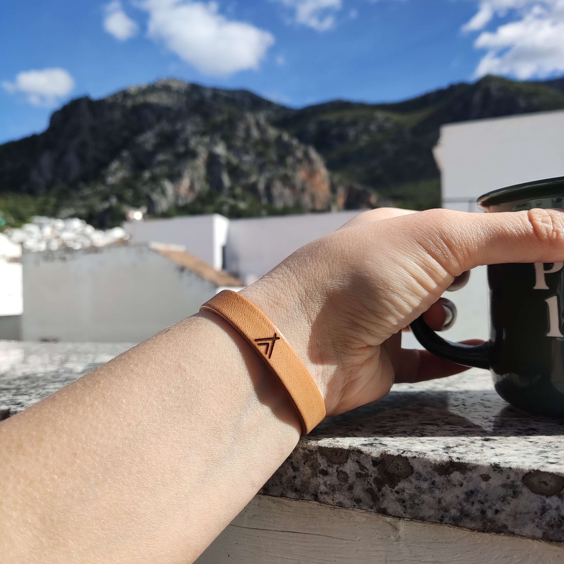 A brown leather bracelet with a tipi engraved on it