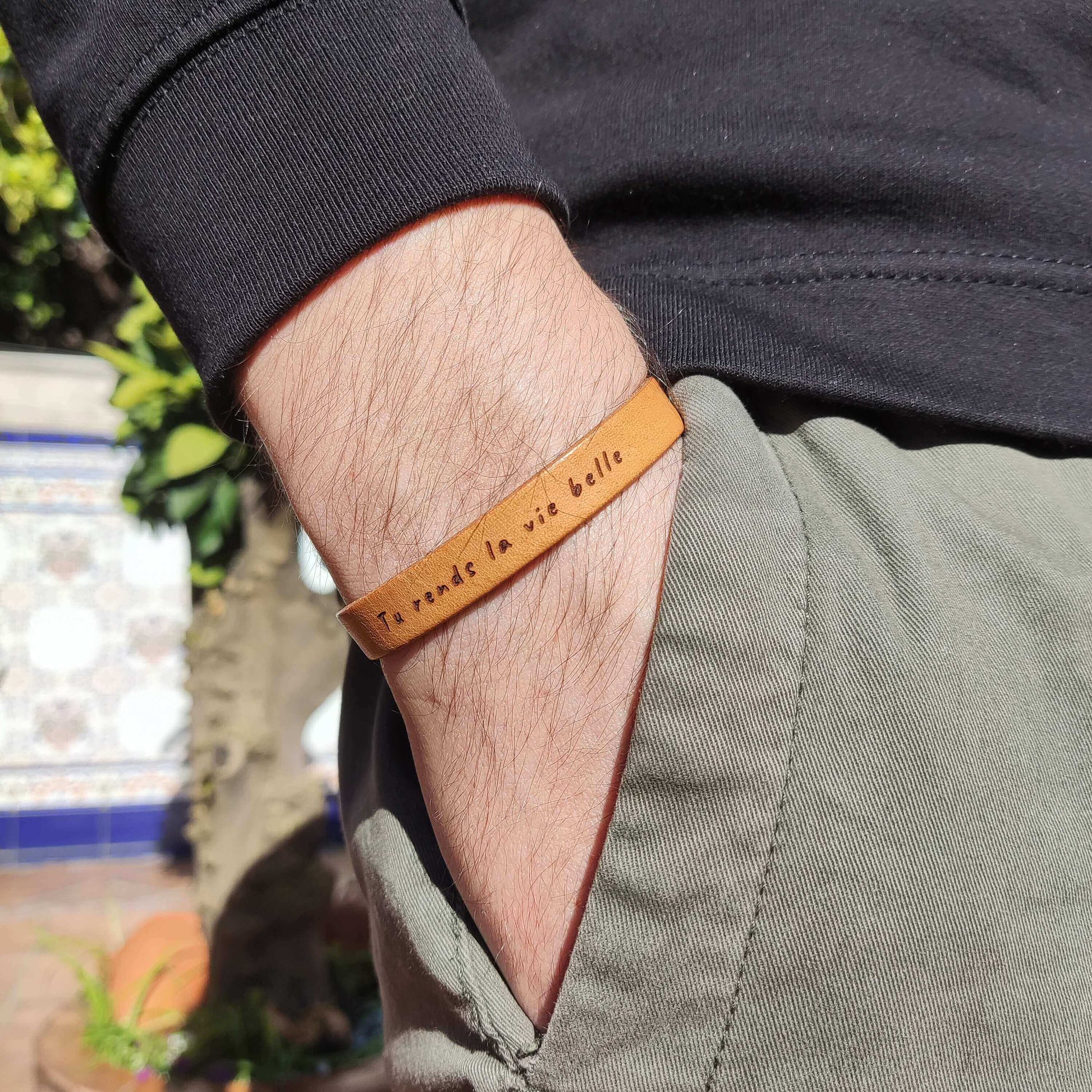 A brown leather bracelet with `Tu rends la vie belle´ engraved on it.