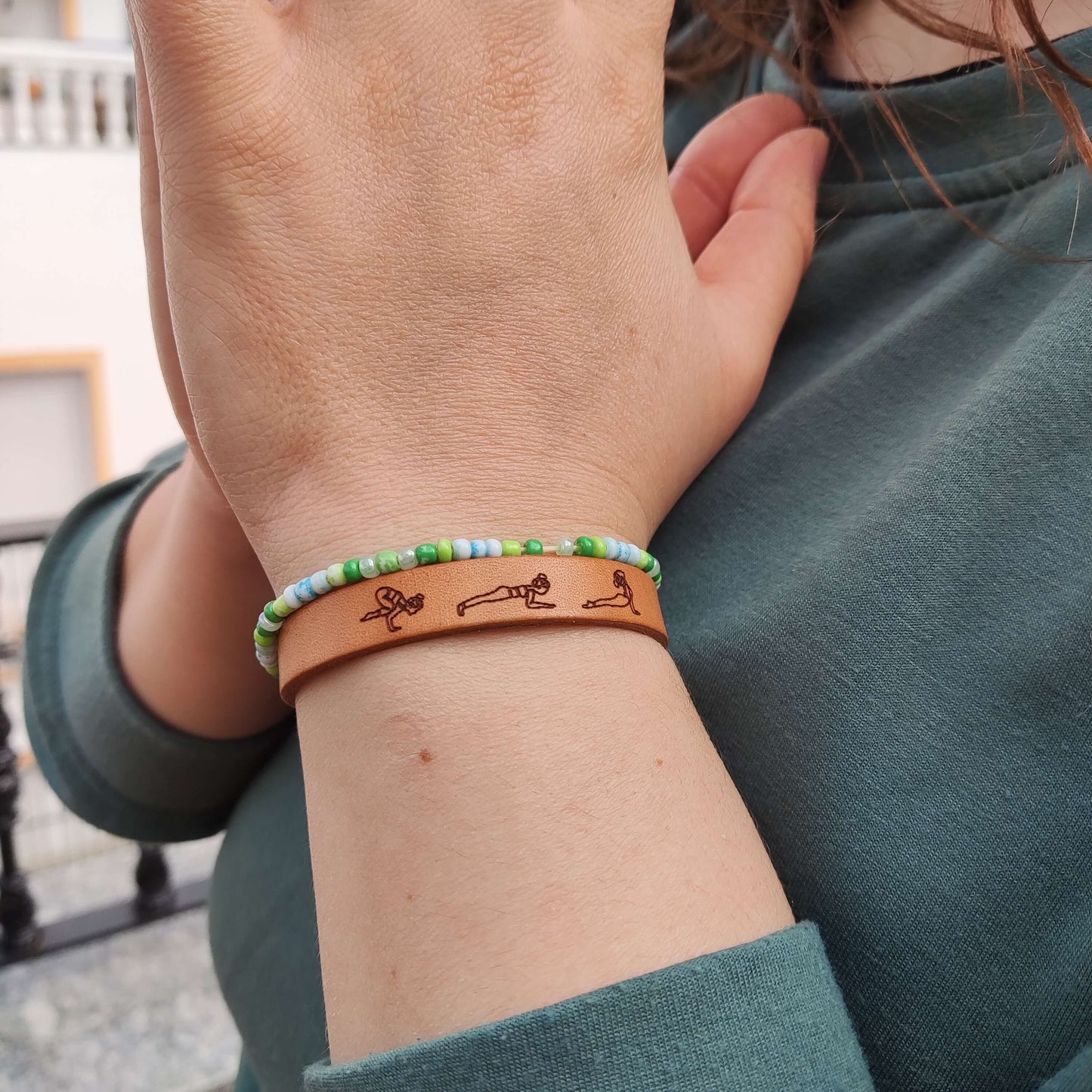 A brown leather bracelet with a Vinyasa Flow Yoga sequence engraved on it.