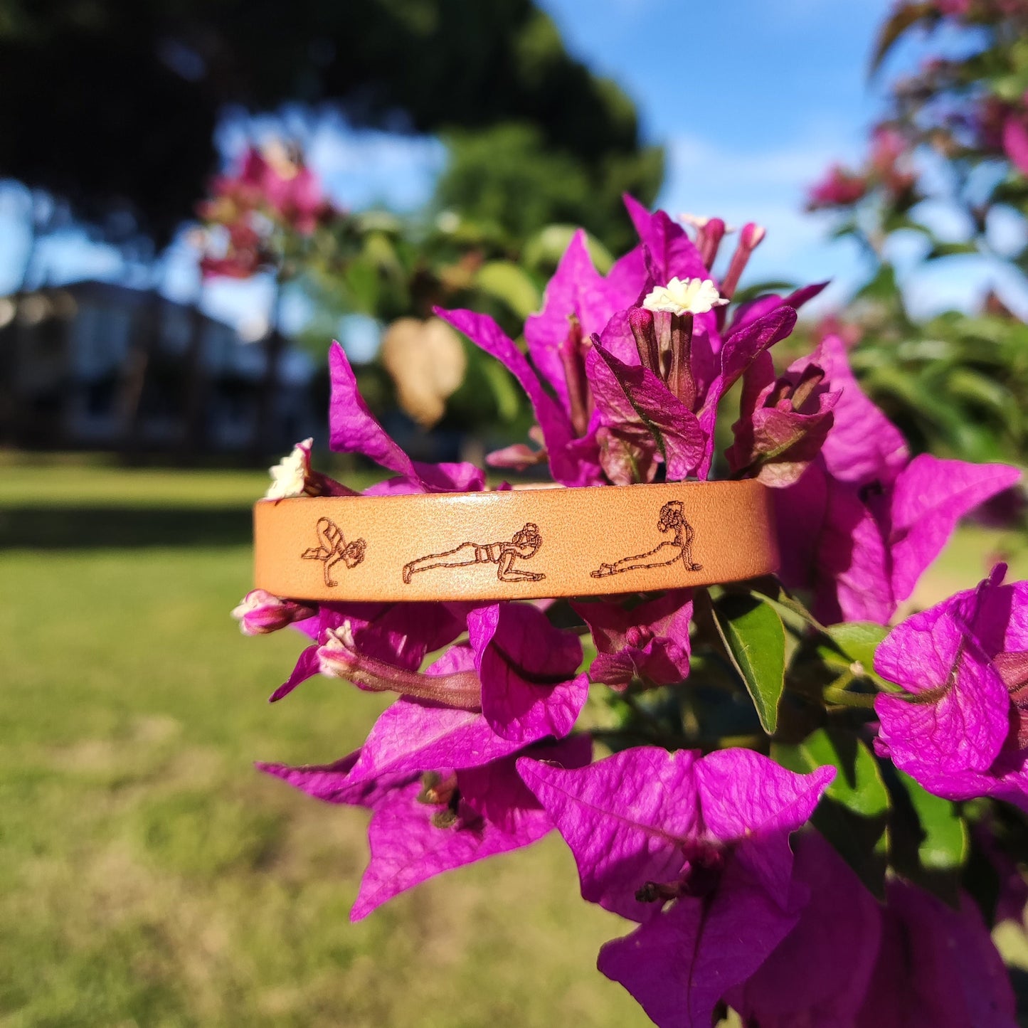 A brown leather bracelet with a Vinyasa Flow Yoga sequence engraved on it.