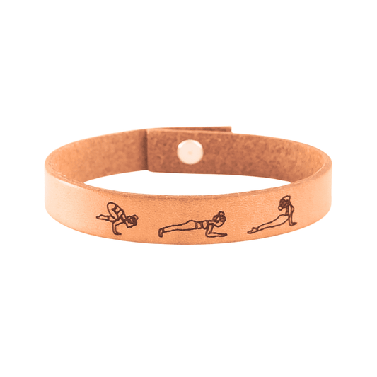 A brown leather bracelet with a Vinyasa Flow Yoga sequence engraved on it.