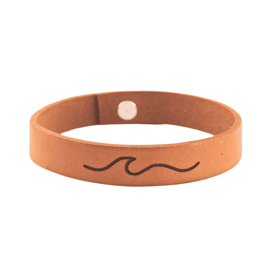 A brown leather bracelet with a wave engraved on it.