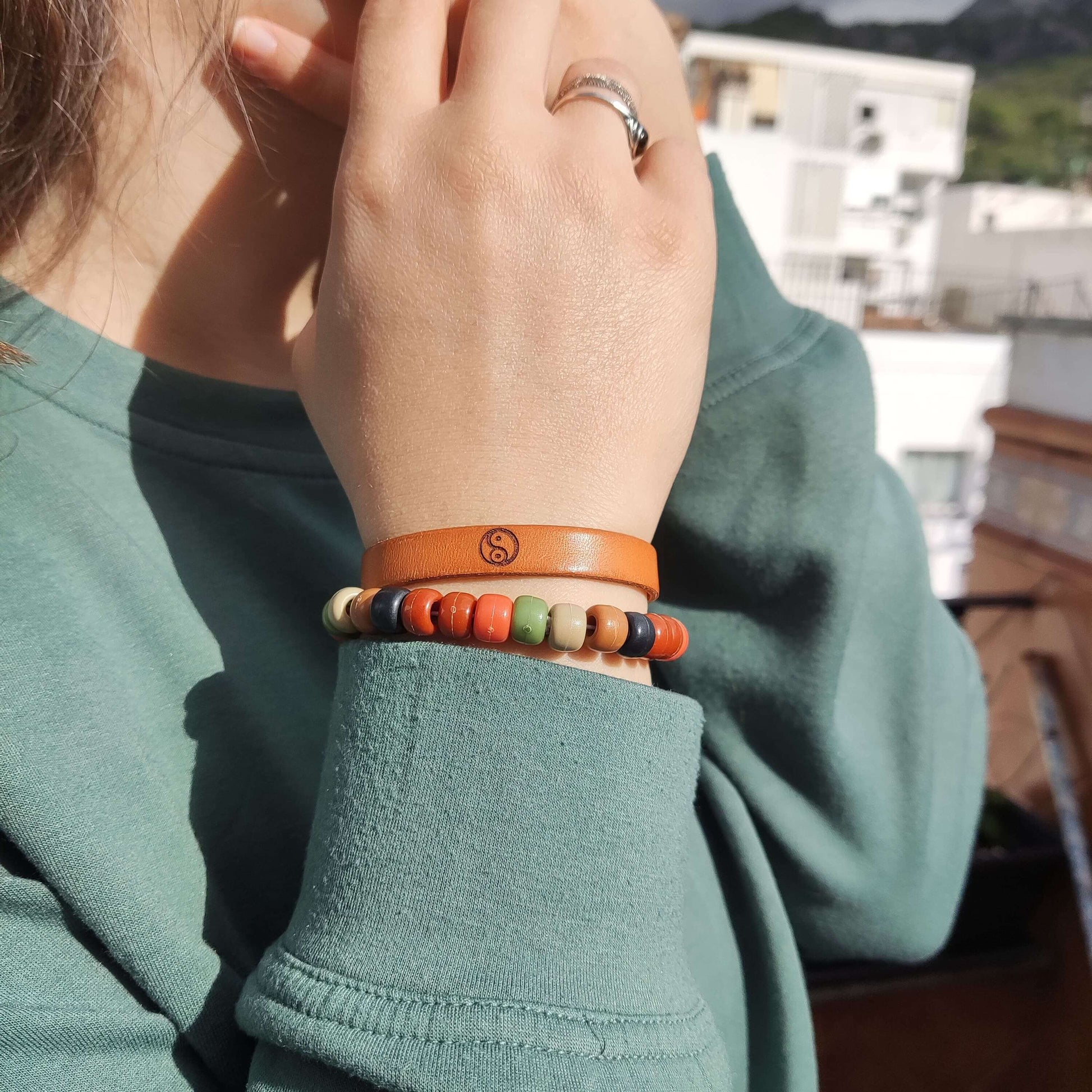 A brown leather bracelet with the Yin Yang symbol engraved on it.
