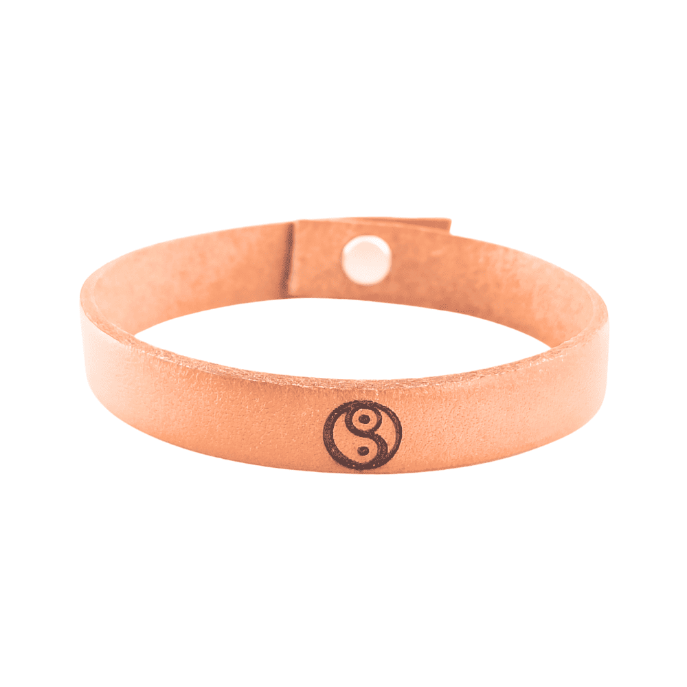 A brown leather bracelet with the Yin Yang symbol engraved on it.