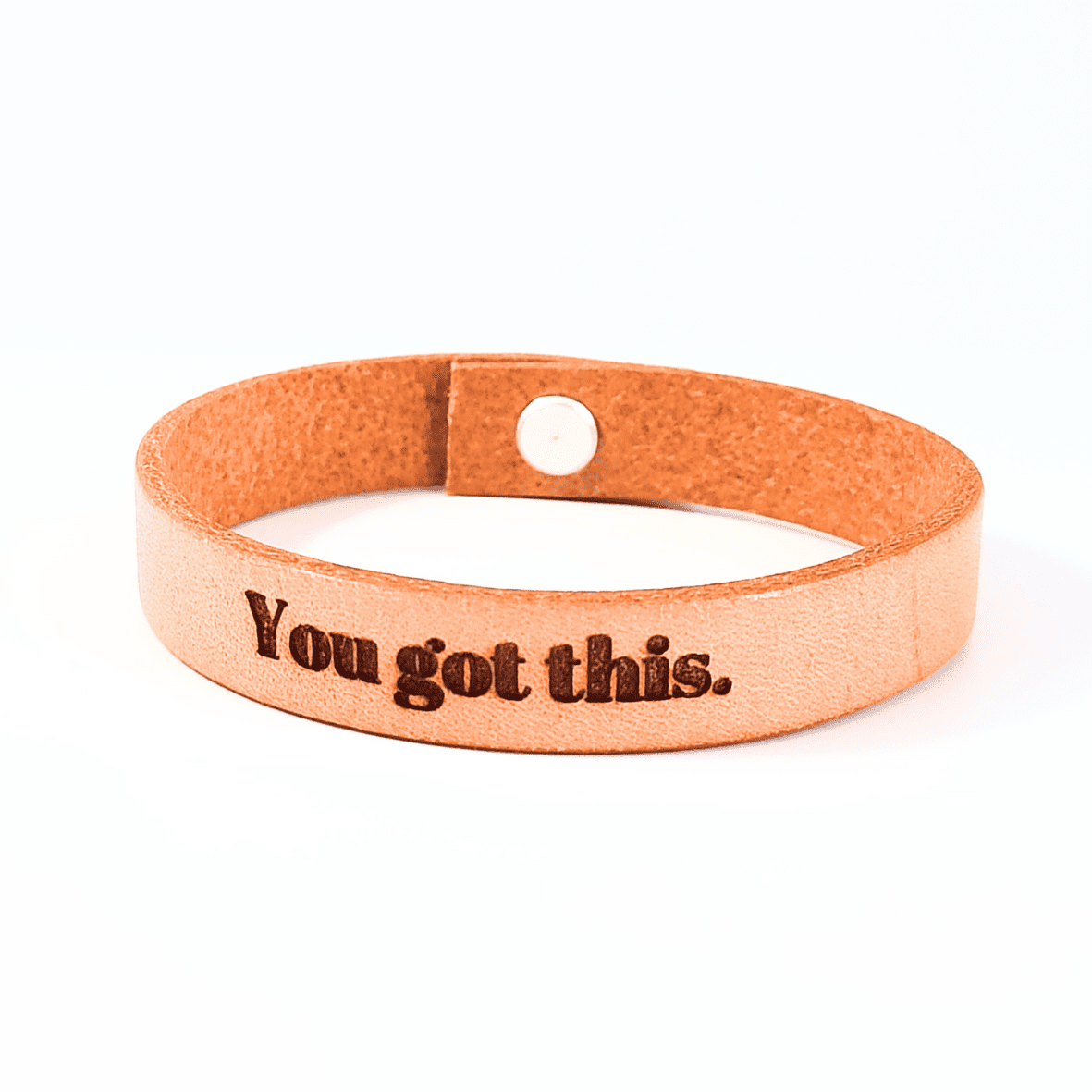 A brown leather bracelet with the text 'You got this.' engraved on it.